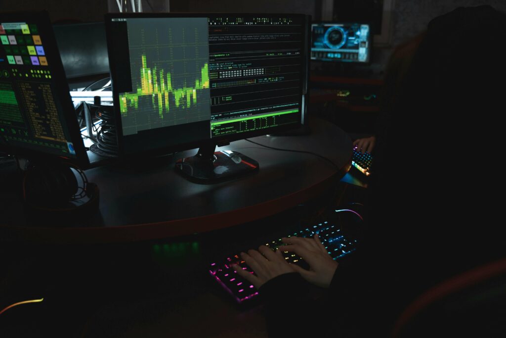 EIn Hacker sitzt vor einem Bildschirm mit Code